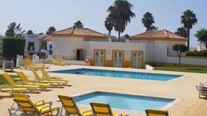 Ein Pool mit gelben Liegestühlen und ein Gebäude mit einem Ziegeldach.