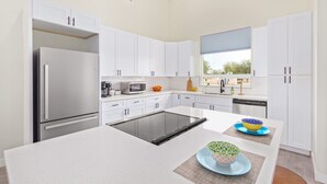 Una cocina moderna con armarios blancos, una isla central y un ventanal que proporciona luz natural.