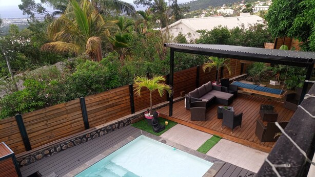 Ein Poolbereich auf dem Dach mit Holzterrasse, Gartenmöbeln und Blick auf die umliegende Landschaft.