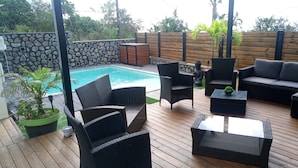 Eine Terrasse im Freien mit Korbmöbeln, einem kleinen Pool und einer Steinmauer.