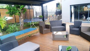 Eine Terrasse im Freien mit Korbmöbeln, einem Trampolin und einer Steinmauer.
