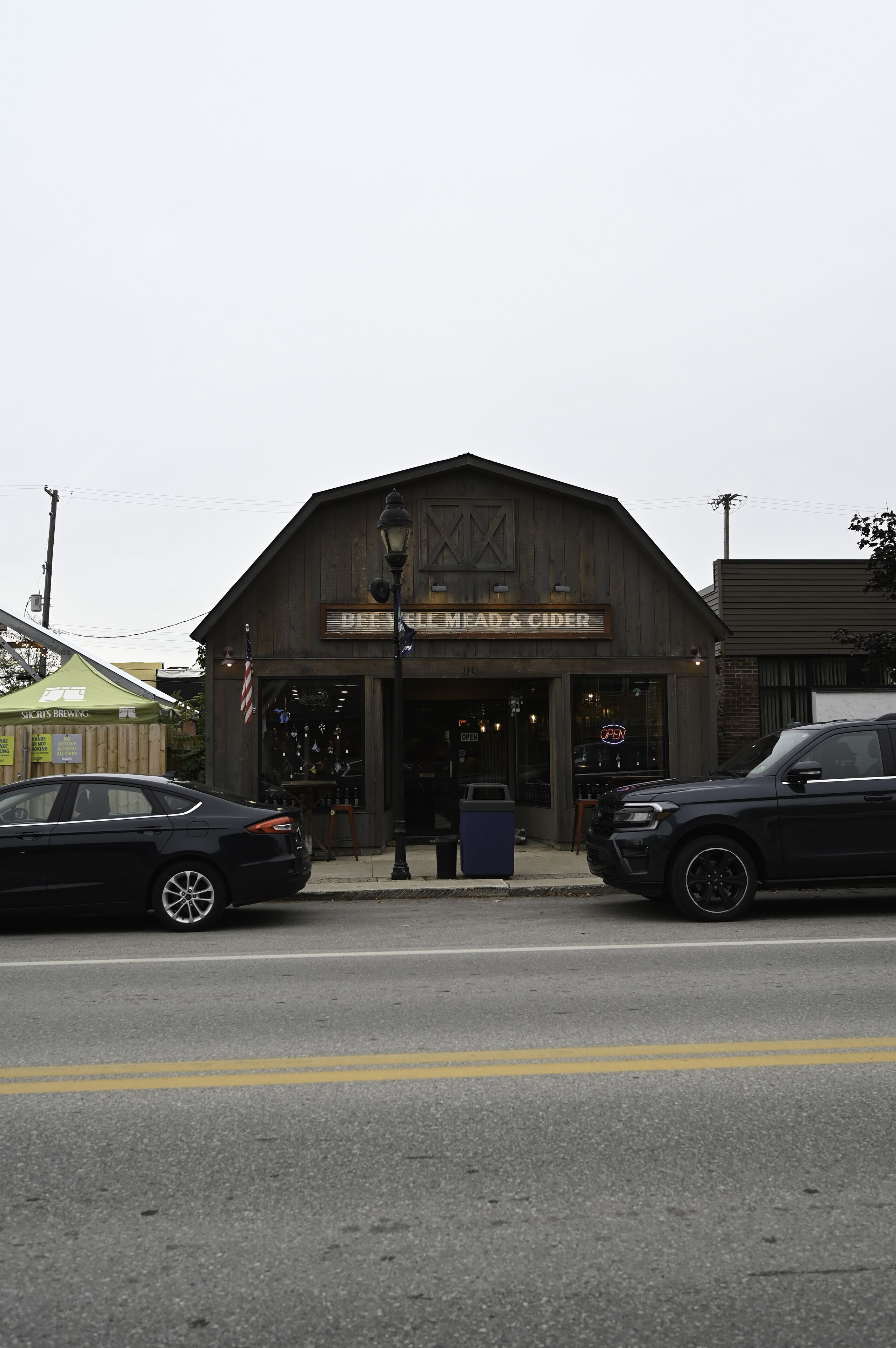 A rustic building with a sign reading "BREAD & CIDER" and a storefront with various items on display.