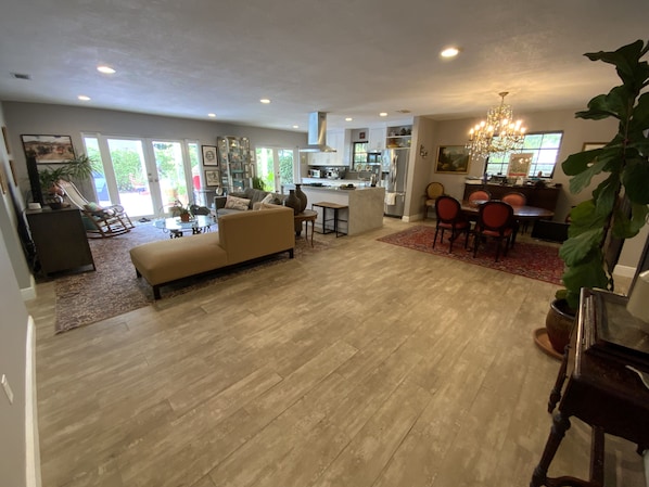 A spacious living area with a large sofa, a dining table with chairs, and a kitchen in the background.