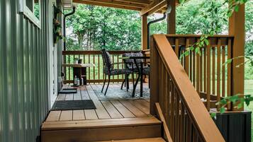 A wooden deck with a staircase leading to a covered area, a table, and chairs.
