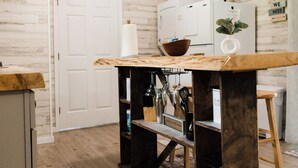 A kitchen with a wooden table, white appliances, and a clock on the wall. - New Tiny Lake Home (Salt Lick)
