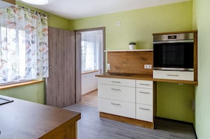 Une cuisine dotée d’un plan de travail en bois, de meubles blancs et d’un four encastré.