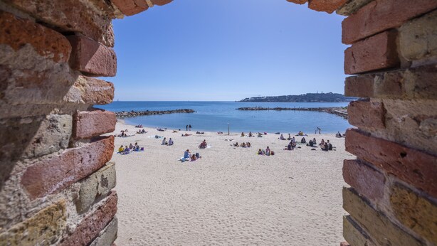 Une vue sur la plage, encadrée par une arche en briques.