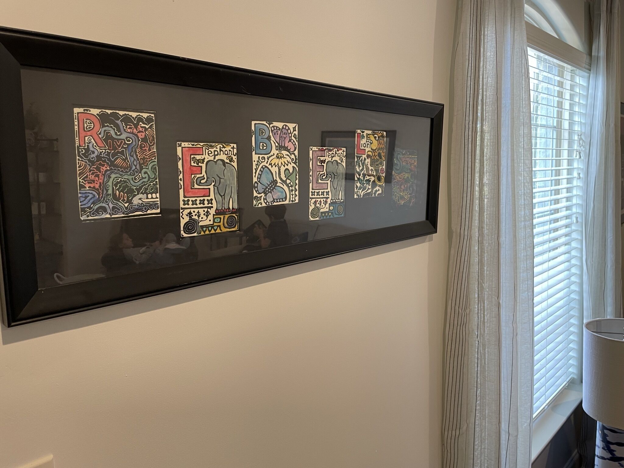 A framed artwork with colorful letters and animal illustrations on a wall.
