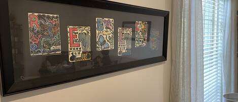 A framed artwork with colorful letters and animal illustrations on a wall.