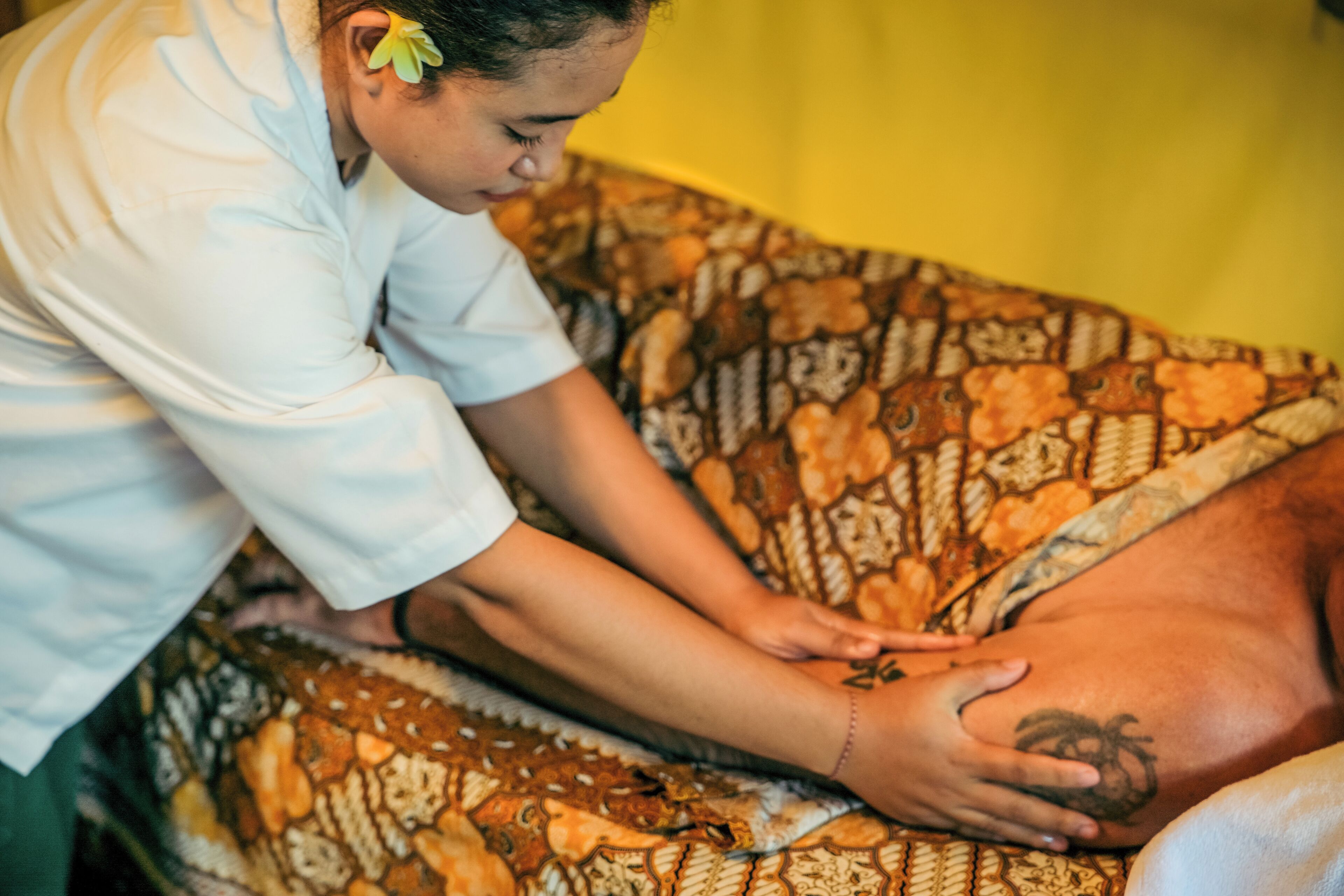 A person receiving a massage on a patterned bedspread.