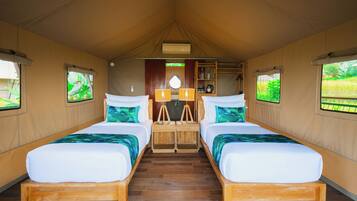Acomodação em tenda com duas camas, uma mesa central e uma prateleira com objetos.