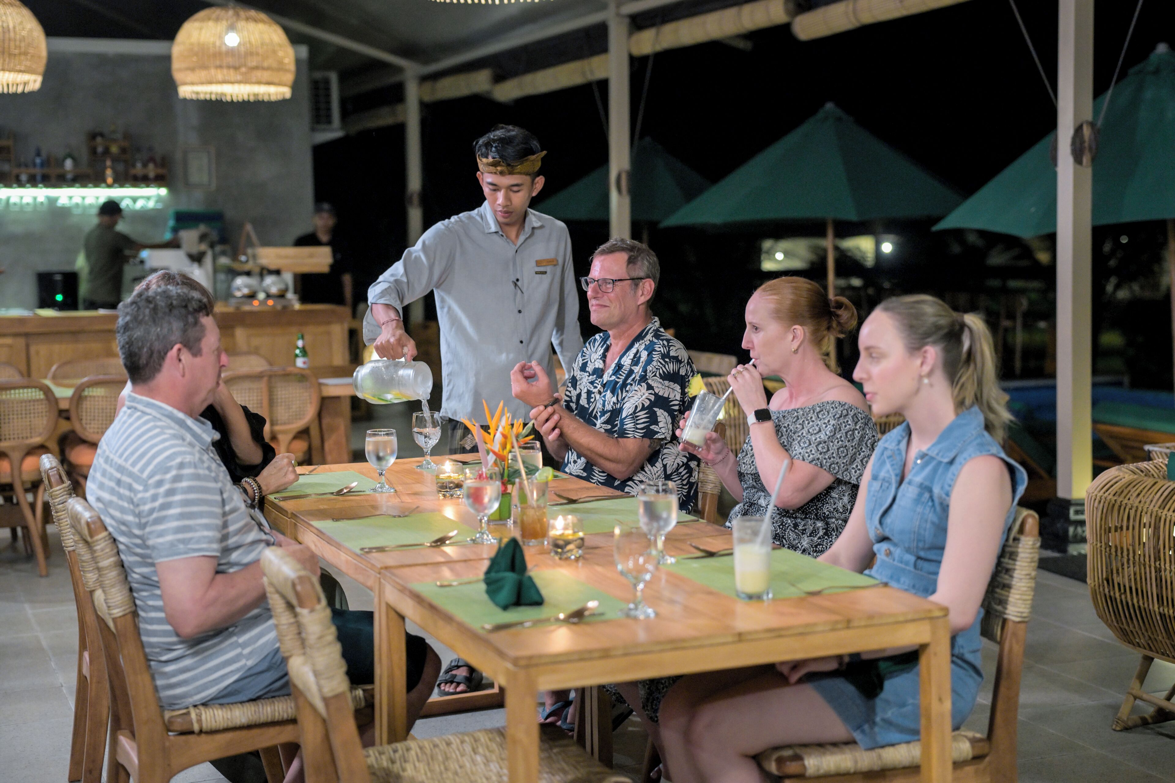 A restaurant with wooden tables and chairs, a bar area, and outdoor umbrellas.