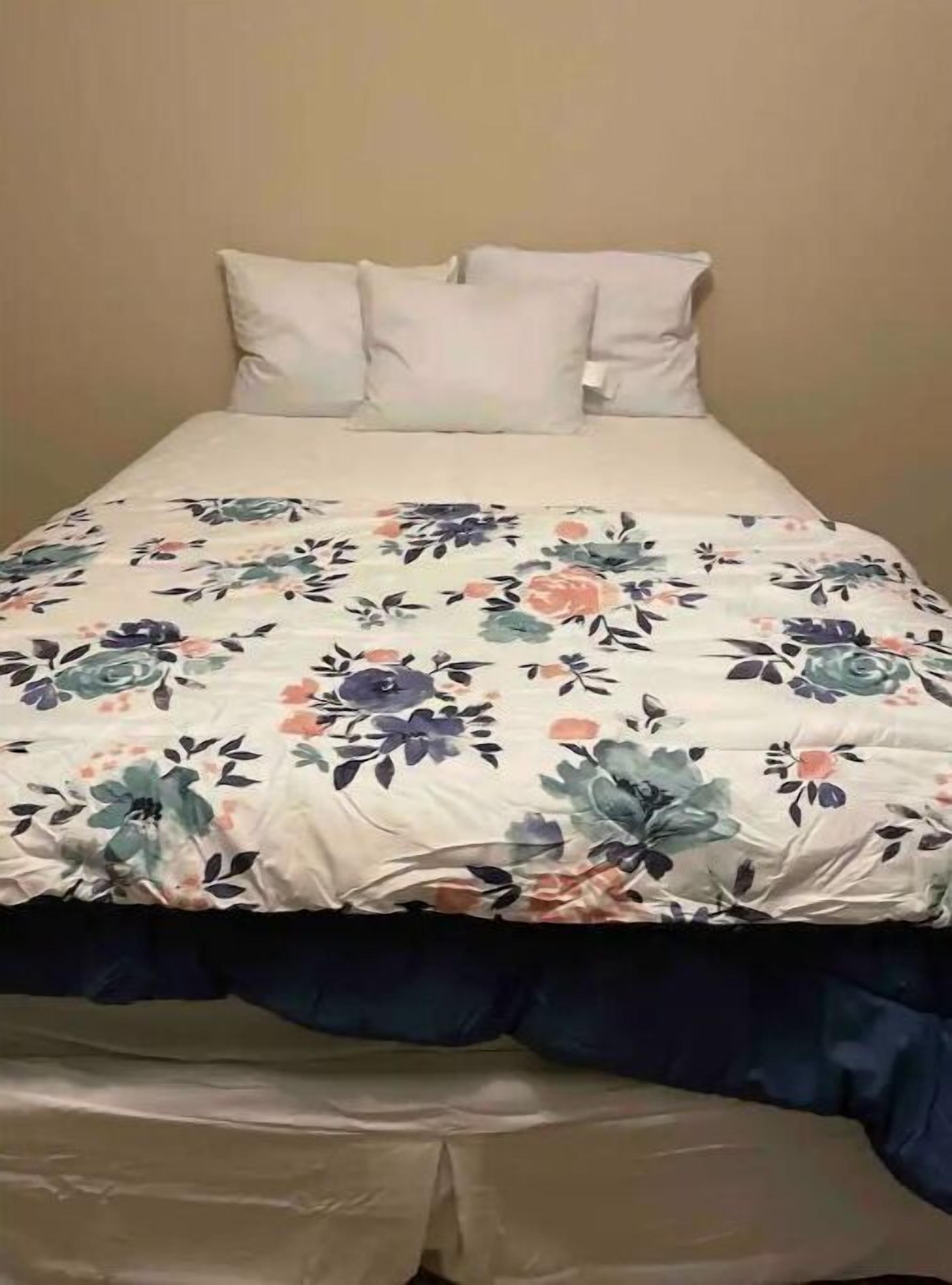 A bed with a floral bedspread and two pillows.