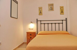 A bedroom with a bed, a nightstand, and three wall-mounted pictures. - Apartment Santa Teresa II (Conil de la Frontera)