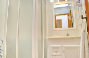 A bathroom with a white vanity, a mirror, and a hairdryer on the wall. - Apartment Santa Teresa II (Conil de la Frontera)