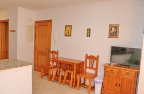 A compact living space with a dining area, a television, and a small kitchen. - Apartment Santa Teresa II (Conil de la Frontera)