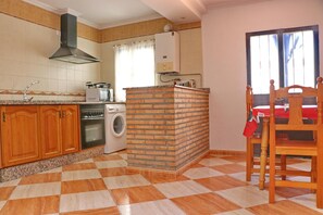A kitchen with a washing machine, oven, and a brick island. - Compass Rose Apartment (Conil de la Frontera)