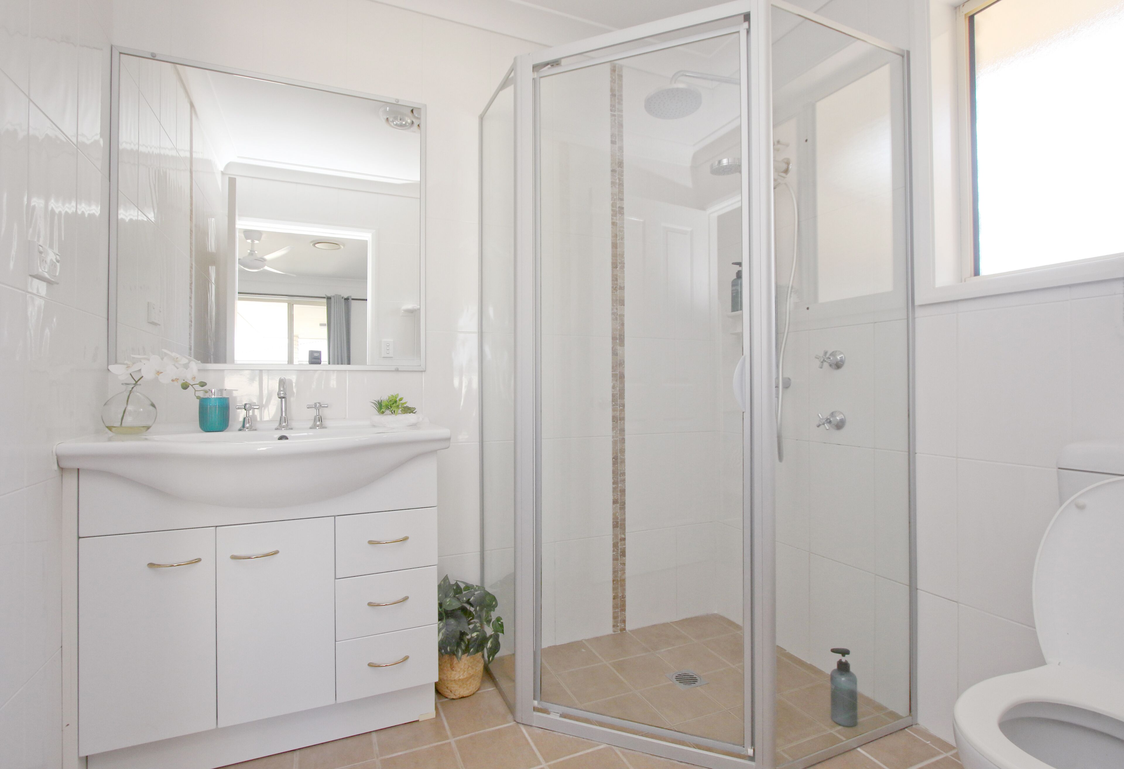 A modern bathroom with a glass-enclosed shower, a white sink, and a large mirror.