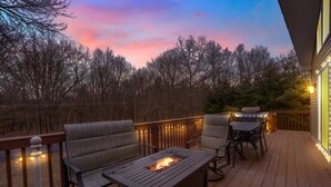 Une terrasse avec un foyer extérieur, des sièges et des guirlandes lumineuses.
