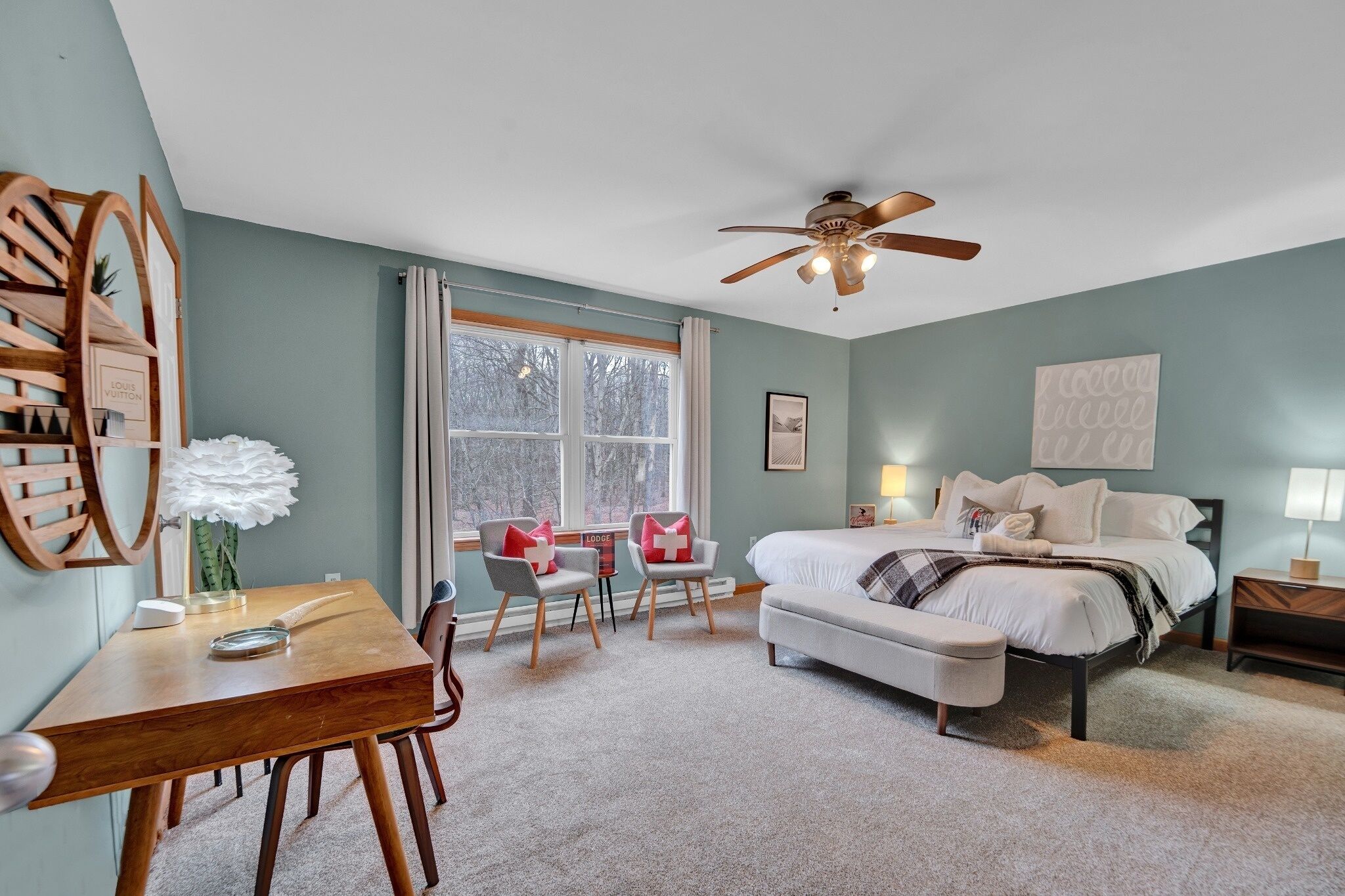 Une chambre à coucher comprenant un lit, un bureau, des chaises, un ventilateur de plafond et une fenêtre.