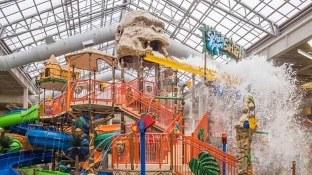 Un parc aquatique intérieur doté de toboggans, d’un jet d’eau et d’une structure de jeux sur le thème des dinosaures.