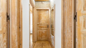 Un pasillo de madera con un diseño de suelo en forma de estrella, flanqueado por puertas de madera que muestran signos de uso.