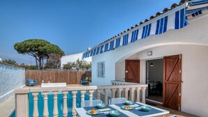 Eine Terrasse mit Tisch für zwei Personen, einer Holztür und Blick auf die Umgebung.