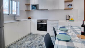 Eine moderne Küche mit weißen Schränken, einer Mikrowelle, einem Backofen und einem Essbereich mit kariertem Tischläufer.