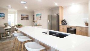 Una cucina moderna con isola centrale, elettrodomestici in acciaio inossidabile e zona pranzo con sgabelli da bar.