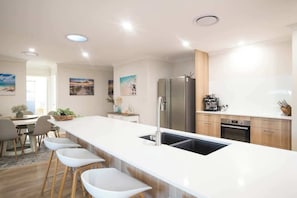 Cocina moderna con una isla central, electrodomésticos de acero inoxidable y una zona de comedor con taburetes de bar.