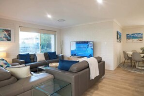 A modern living room with a sofa set, a glass coffee table, and a flat-screen TV.