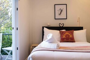 Une chambre à coucher avec un lit, un tableau encadré, une décoration en forme de cœur et une fenêtre donnant sur un paysage verdoyant.