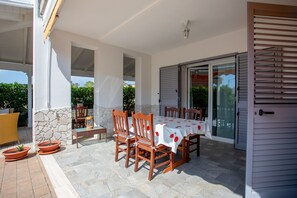 Eine Terrasse im Freien mit einem für vier Personen gedeckten Tisch, umgeben von Holzstühlen.