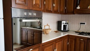 Una cocina con armarios de madera, horno de acero inoxidable, cafetera y una cesta sobre la encimera.