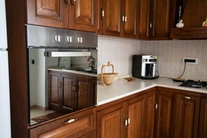 Køleskab, ovn, køkkentøj/tallerkener/redskaber, spisebord