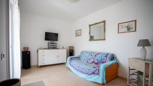Una sala de estar con sofá, televisor, mueble y espejo.