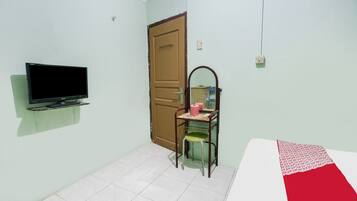 A room with a bed, a television mounted on the wall, a door, and a chair with a mirror.