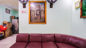 Una habitación con un sofá de cuero púrpura, un cuadro religioso enmarcado y un cartel de 'No Fumar'.