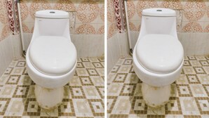 Un inodoro con asiento y tapa blancos, frente a un suelo y pared de baldosas estampadas.