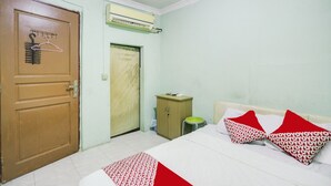 Un dormitorio con cama, almohadas, armario, aire acondicionado y una puerta.
