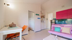 A compact living space with a kitchenette, a dining area, and a seating area with a sofa. - Cala Azzurra in Fetovaia (Campo nell'Elba)