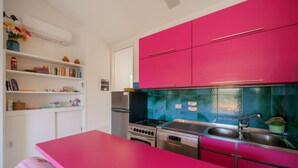 A kitchen with pink cabinets, a stove, and a sink. - Cala Azzurra in Fetovaia (Campo nell'Elba)