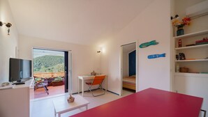 A modern room with a TV, a dining table, a chair, and a bed. There is a balcony with a view of the hills. - Cala Azzurra in Fetovaia (Campo nell'Elba)