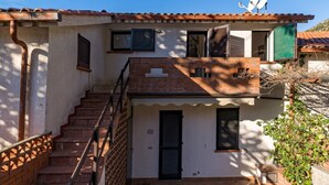 A two-story building with a brick staircase leading to a balcony. - Cala Azzurra in Fetovaia (Campo nell'Elba)