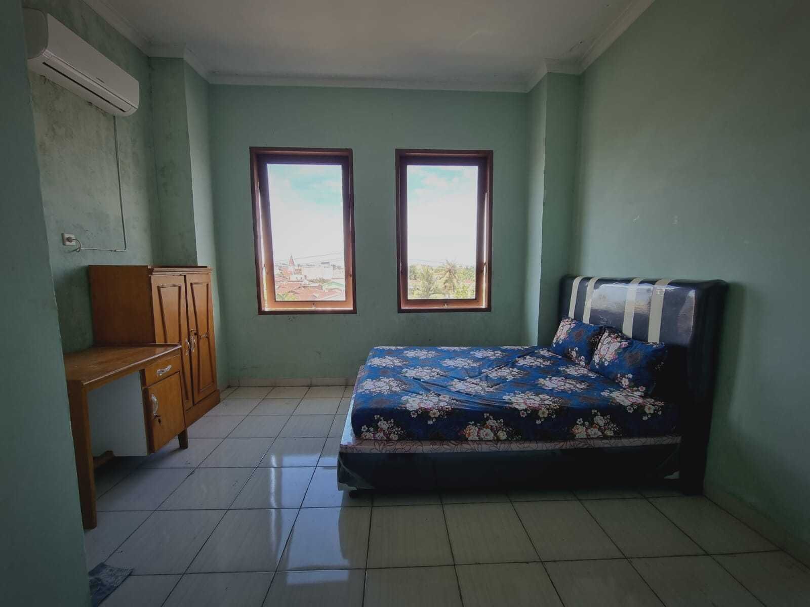 Une chambre à coucher comprenant un lit, un bureau, deux fenêtres et un appareil de climatisation.