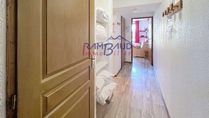 A hallway with wooden doors, a bed with white linens, and a bathroom visible in the background. - Apartment 2 rooms 4 beds -Swimming pool - Footpath (VALLOIRE)