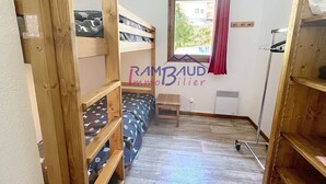 A small, compact room with bunk beds, a window with a curtain, and a radiator. - Apartment 2 rooms 4 beds -Swimming pool - Footpath (VALLOIRE)