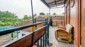 A balcony with a wooden bench, a metal railing, and a view of a building with a tiled roof. - OYO Homes 90996 Desa Wisata Pulesari Syariah (Turi)
