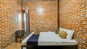 A room with a brick wall, a bed with white bedding, a TV on a small table, and a window. - OYO Homes 90996 Desa Wisata Pulesari Syariah (Turi)
