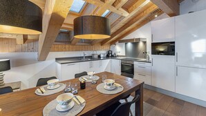 A modern kitchen with wooden beams, a dining area with a wooden table, and a large window. - MONT BLANC - A08 - apartment for 8 people with 3 bedrooms (LA CHAPELLE D ABONDANCE)